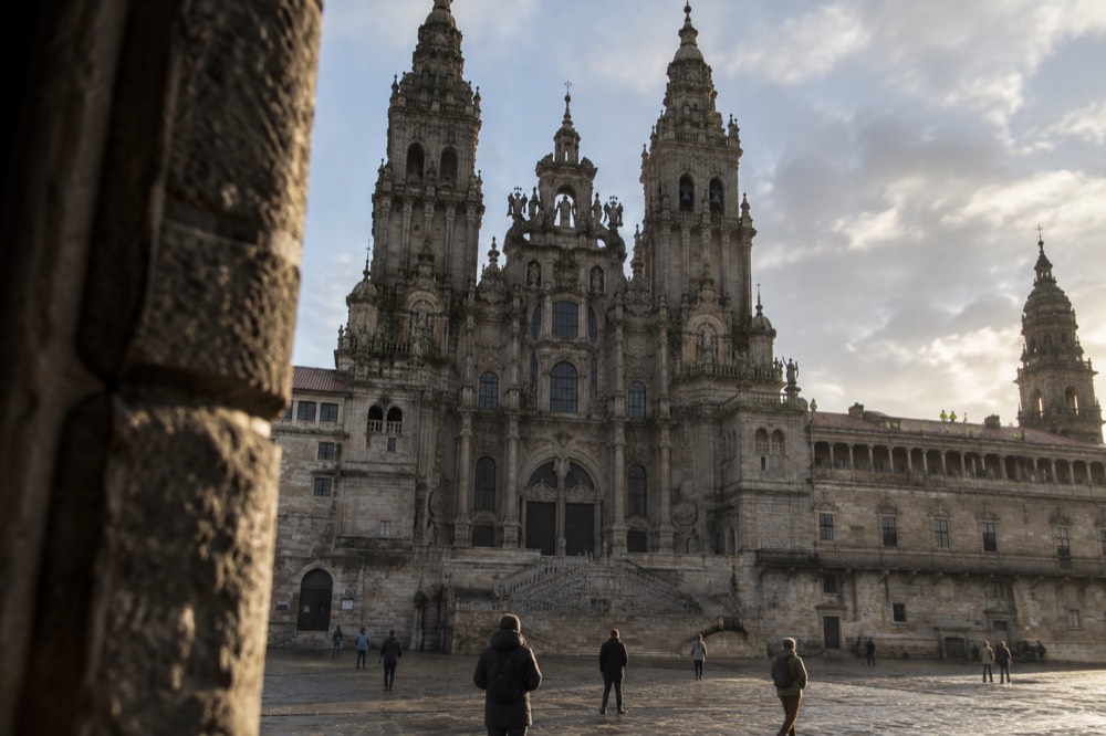 Guided visitors in high-visibility vests walking along the stone rooftop terrace beside the cathedral towers