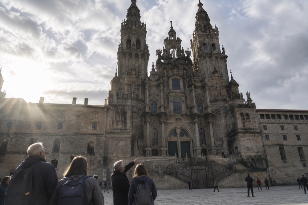 A guide pointing out carved stone figures on a cathedral doorway to a small group of visitors