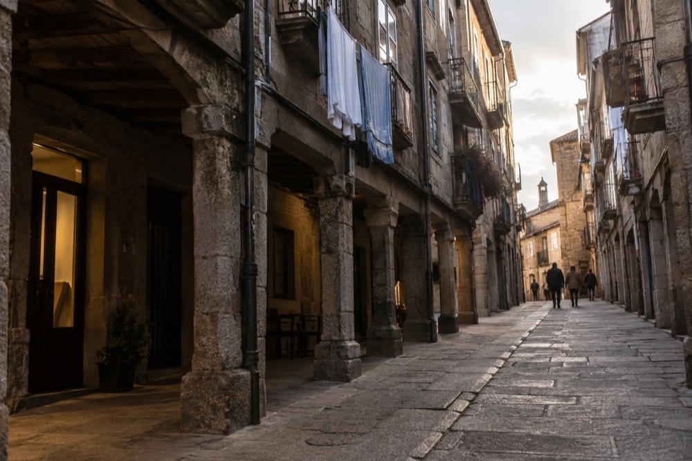 A narrow granite street in the old town with arcades and hanging laundry above the doorways