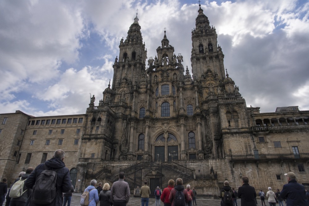 Travelers on a guided walking tour looking up at the baroque Cathedral facade from the square