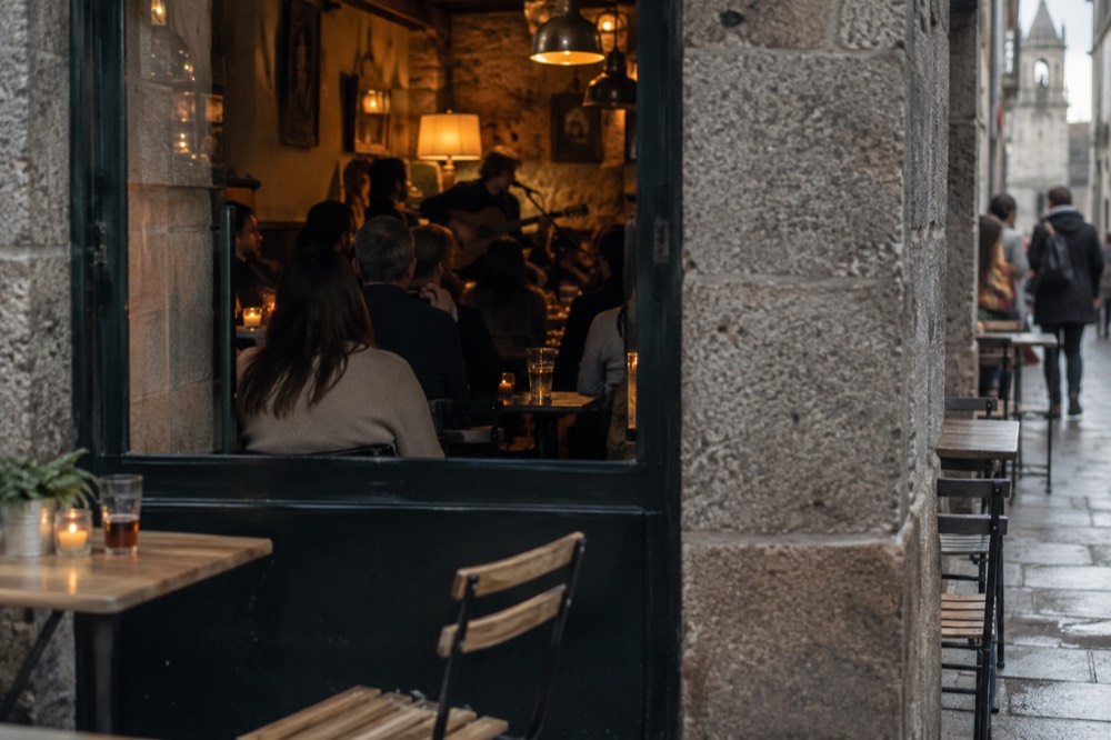A singer with a guitar performing inside a small crowded tapas bar at night
