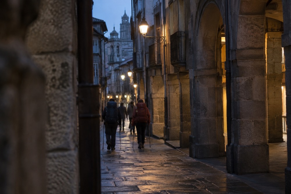 Pilgrims with backpacks and walking staffs arriving in the old town of Santiago de Compostela