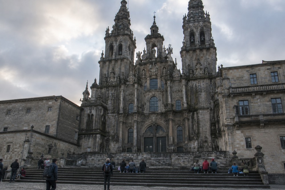 Pilgrims resting with their backpacks on the steps in front of Santiago Cathedral