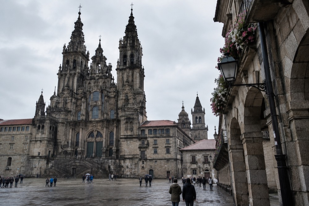 Narrow granite street with arcades and hanging flower baskets in Santiago de Compostela