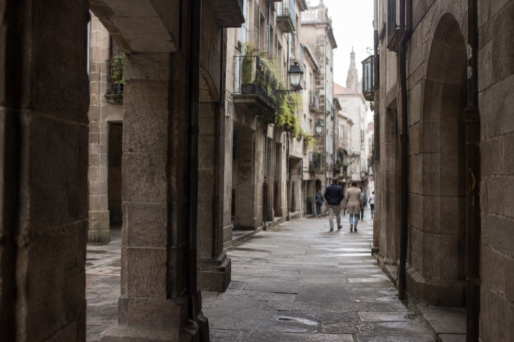 Narrow granite street with wrought-iron balconies in the old town of Santiago de Compostela