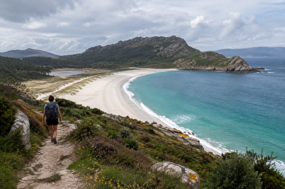A white crescent beach and turquoise water on the Cies Islands seen from a hilltop path