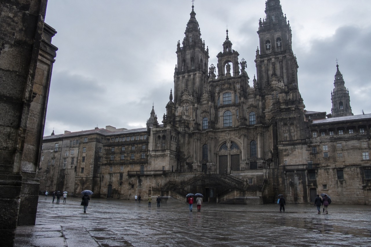 Wet cobblestone square in Santiago de Compostela with the cathedral towers behind light rain