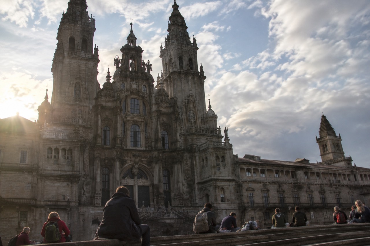Pilgrims resting on the stone steps of the Cathedral of Santiago de Compostela in Praza do Obradoiro