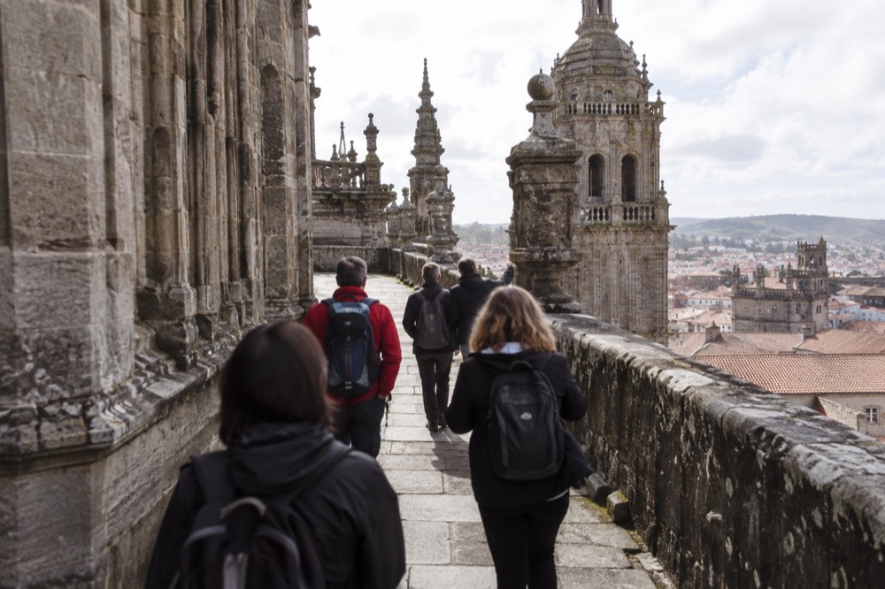 Guide leading visitors on the rooftop of Santiago de Compostela Cathedral with the old town below
