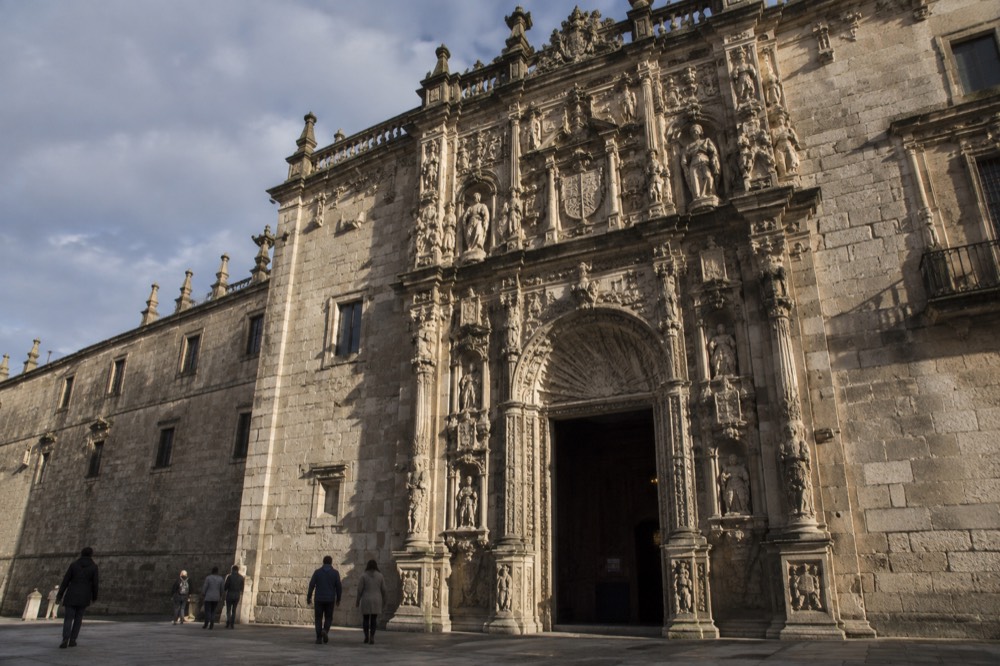 The ornate facade of the Hostal dos Reis Catolicos parador on Praza do Obradoiro at dusk