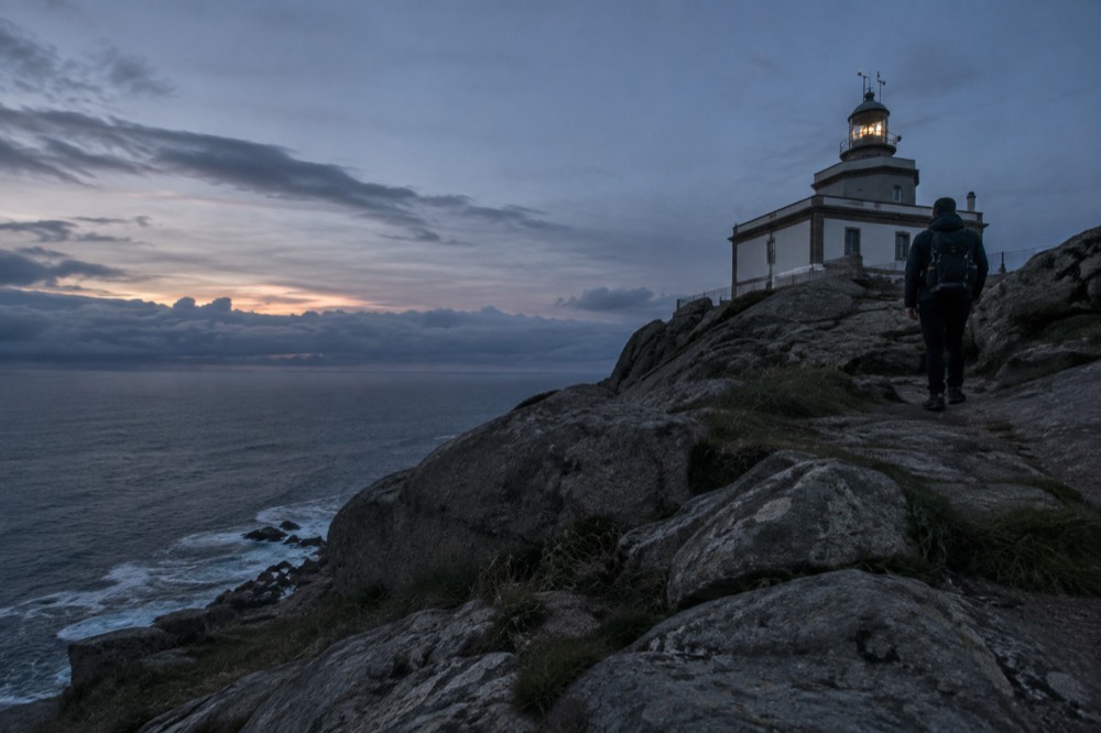 Pilgrim standing at the Fisterra lighthouse above the Atlantic Ocean at the end of the Costa da Morte