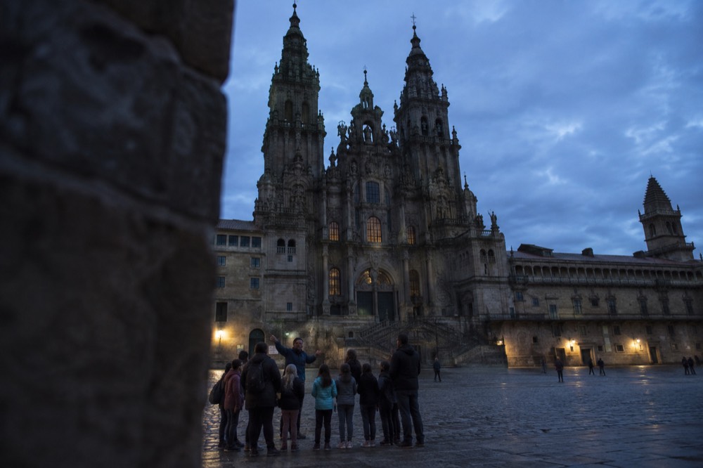 A tour guide speaking to a small group including children in a stone plaza