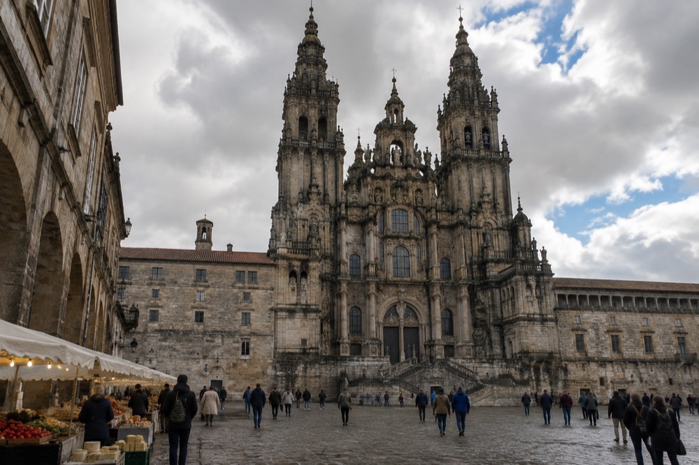 Stalls of cheeses, peppers and fresh fish under the stone halls of a Galician food market