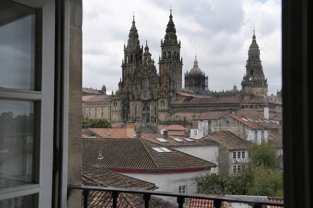 A guest room window looking out over tiled rooftops toward cathedral towers in Santiago de Compostela